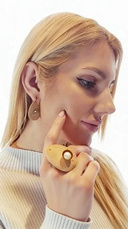 Discover natural elegance with these unique dangle earrings that combine wood and pearls in a stunning design. Designed by Greek Jewelry Designer Aikaterini Chalkiadaki, these handmade jewelry pieces offer a modern take on classic elegance.

Each earring features an oval wooden base in a natural brown color, complemented by a square metal element with a white pearl at its center. This combination creates a wonderful contrast of textures and colors that catches the eye. The natural warmth of the wood harmonizes perfectly with the shine of the pearls, creating a piece of jewelry that is ideal for both everyday wear and special occasions.