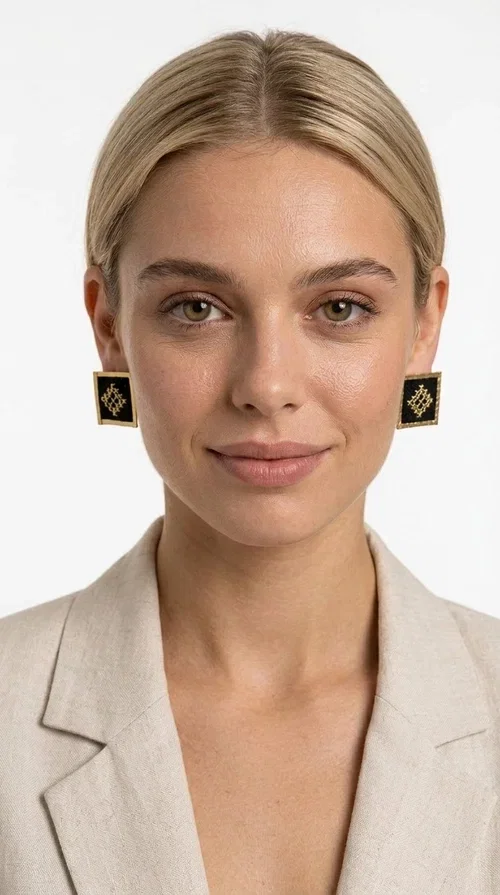 Embroidered statement earrings with geometric patterns are the ideal choice for anyone who wants to add a touch of individuality and character to their look. The square black fabric with gold embroidered details in a diamond-shaped geometric motif creates a striking result that combines the traditional art of embroidery with modern design. Designed by Greek Jewelry Designer Aikaterini Chalkiadaki, these handmade earrings are a piece with a strong aesthetic identity that evokes folk tradition.

Made of brass and fabric, these earrings combine two materials with different textures and character. The gold brass frame surrounds the black fabric square, while the embroidered geometric pattern gives depth and richness to the composition. The result is a stud earring that is comfortable to wear and automatically becomes the focal point of any look.

They suit both casual and formal looks equally well — from a simple linen jacket to an evening outfit. Also ideal as a gift for women who love unique, handmade jewelry with a Greek aesthetic.