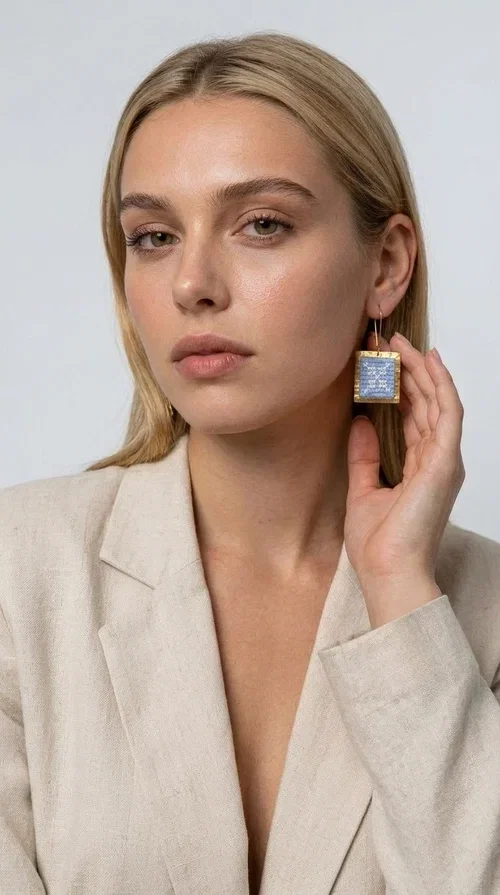 The embroidered statement earrings with geometric designs in light blue are a bold choice for every woman who wants to express herself through her jewelry. Designed by Greek Jewelry Designer Aikaterini Chalkiadaki, these striking handmade earrings combine the traditional art of embroidery with a modern, geometric aesthetic.

Their square shape, featuring a gold-tone brass hoop, highlights the light blue embroidered fabric adorned with delicate geometric details — a result that evokes Greek folk art and a folklore aesthetic. Each pair is unique thanks to its handmade craftsmanship, making it a true treasure for your collection.

Ideal for weddings, christenings, formal occasions, and even for elevating an everyday look, these earrings pair beautifully with white, ecru, or blue outfits. Lightweight to wear and comfortable to have on.
