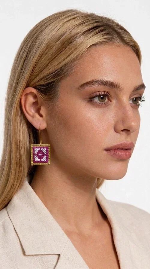 The embroidered statement earrings in a vibrant magenta shade are the definition of jewelry that never goes unnoticed — a bold choice for those who love to express themselves through their style.

Designed by Greek Jewelry Designer Aikaterini Chalkiadaki, these striking handmade earrings combine geometric embroidered patterns in magenta and white, set within a square brass frame in a gold hue. The embroidery technique adds depth and texture to the piece, bringing forward a folk and folklore aesthetic that nods to Greek tradition in a modern way.

The dangling design with a delicate hook lets the earrings sway elegantly, elevating every look — from casual everyday outfits to evening outings, weddings, or festive occasions. The bold magenta hue pairs beautifully with neutral colors (white, beige, black) as well as with daring color combinations.