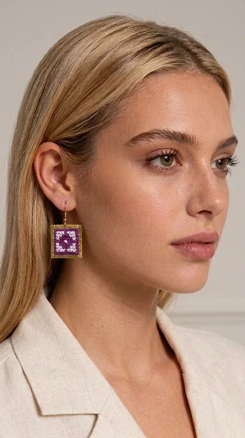 The embroidered statement earrings with geometric designs in magenta are a bold choice for every woman who wants to express herself through her accessories. Designed by Greek Jewelry Designer Aikaterini Chalkiadaki, these handmade earrings combine the traditional art of embroidery with a modern, folk-inspired aesthetic that stands out immediately.

Each pair features a square shape with a gold-tone brass frame and embroidered fabric in a vivid magenta hue with white details that create a striking geometric pattern. The texture of the embroidery adds depth and character, making them stand out from conventional dangle earrings. Their vibrant magenta shade makes them ideal for creating an impressive look, whether for everyday or formal outfits.

They pair perfectly with white or neutral outfits, adding color and personality to any look. Ideal for weddings, christenings, nights out, or even a creative office look. They also make a unique gift idea for women with distinctive taste.