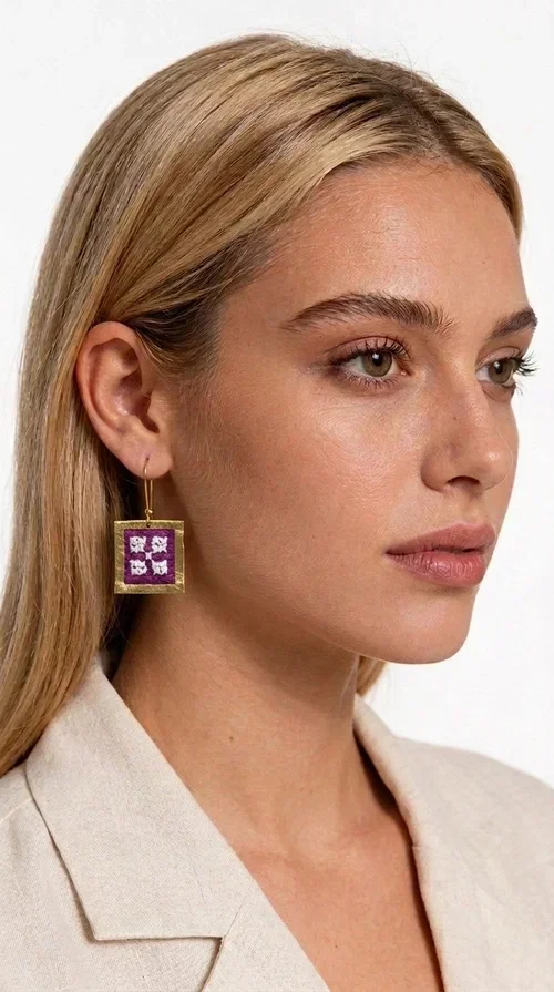 The embroidered statement earrings with geometric patterns in magenta are the ideal choice for every woman who wants to express herself through her style. Designed by Greek Jewelry Designer Aikaterini Chalkiadaki, these handmade earrings combine the traditional art of embroidery with a modern, geometric aesthetic that instantly catches the eye.

The square brass frame in a gold finish surrounds an embroidered fabric in a bold magenta color with white geometric details, creating a bold, folklore-inspired result. The dangling design with hook makes the earrings lightweight to wear and comfortable for all-day use, while their size is perfect for making a statement without being over the top.

Ideal for weddings, christenings, festive events, but also for a casual chic look with a white shirt or dress. The magenta color pairs beautifully with neutral colors such as beige, white, and black.