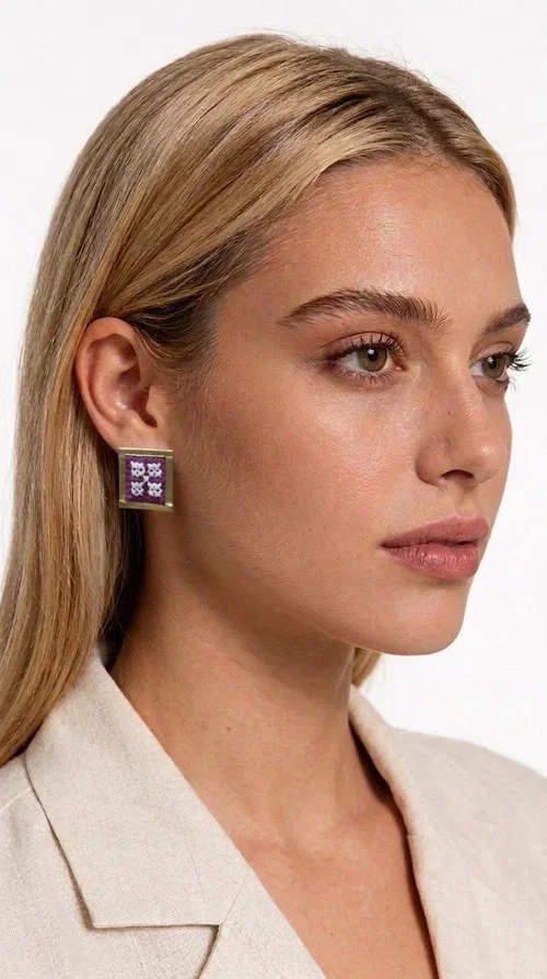 The embroidered statement earrings with geometric designs in magenta are a bold choice for every woman who wants to express herself through her style. Designed by Greek Jewelry Designer Aikaterini Chalkiadaki, these handmade stud earrings combine folklore aesthetics with contemporary geometric composition, creating a result that immediately catches the eye.

Made from brass and fabric, they feature a square frame with a golden finish and an embroidered inner motif in a striking magenta shade, with delicate floral-geometric details reminiscent of traditional Greek folk art. The result is a jewelry piece with character and depth, ideal for elevating even the simplest outfit.

Perfect for weddings, christenings, nights out, or everyday looks that call for something extra, these earrings pair beautifully with white, black, or neutral clothing that lets the jewelry take center stage.