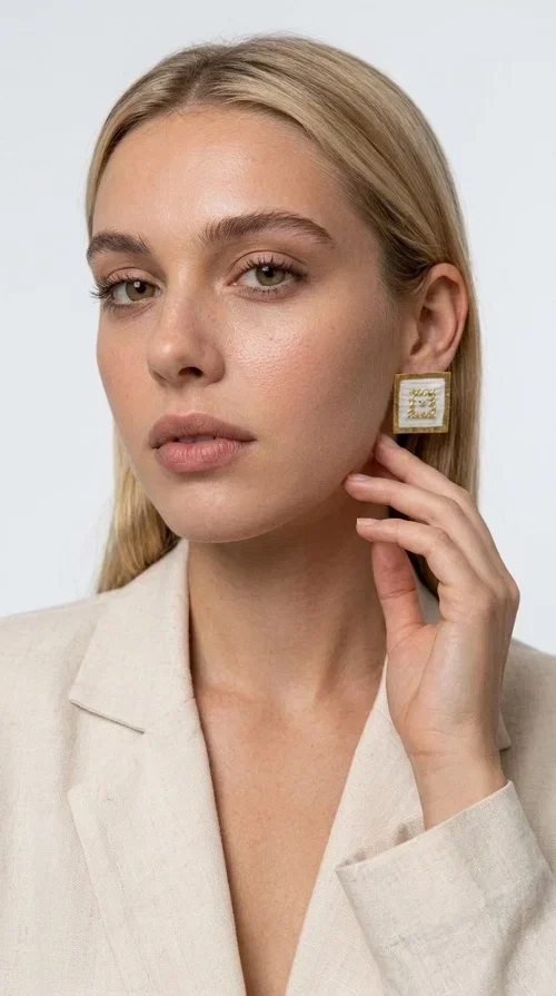 Embroidered statement earrings with geometric patterns are the ideal choice for those seeking an accessory that combines folk tradition with a modern, minimalist aesthetic. Designed by Greek Jewelry Designer Aikaterini Chalkiadaki, these handmade stud earrings are a tribute to craftsmanship and Greek creativity.

Made from brass and fabric, the earrings feature a square shape on a white background with gold embroidery forming geometric motifs inspired by folk tradition. The result is a jewelry piece with strong character, lightweight to wear and particularly striking in appearance — ideal for both casual outfits and more formal occasions such as weddings, christenings, or professional events.

They pair perfectly with white, beige, or earth-tone clothing, while their square shape adds a modern, geometric element that elevates any look. A perfect gift for women who appreciate handmade jewelry with a Greek soul.