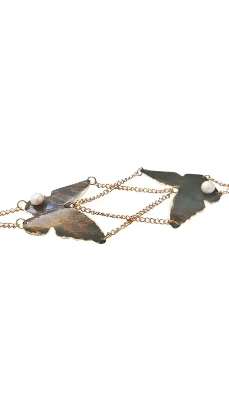 The handwritten handmade bracelet with butterfly is a unique piece of jewelry that combines the elegance of nature with modern aesthetics. Designed by Greek Jewelry Designer Aikaterini Chalkiadaki, this striking women's bracelet features two detailed brass butterflies with a black patina that gives them a vintage character.

The butterflies are connected by a delicate brass chain and adorned with white pearls that add a touch of elegance and brightness. The black patina creates beautiful color contrasts, while the handwritten crafting technique makes each piece unique.

The bracelet is ideal for everyday wear or special occasions, adding an artistic character to any look. It pairs perfectly with other handmade jewelry pieces and makes a wonderful gift choice for women who appreciate Greek artistry and handmade jewelry.