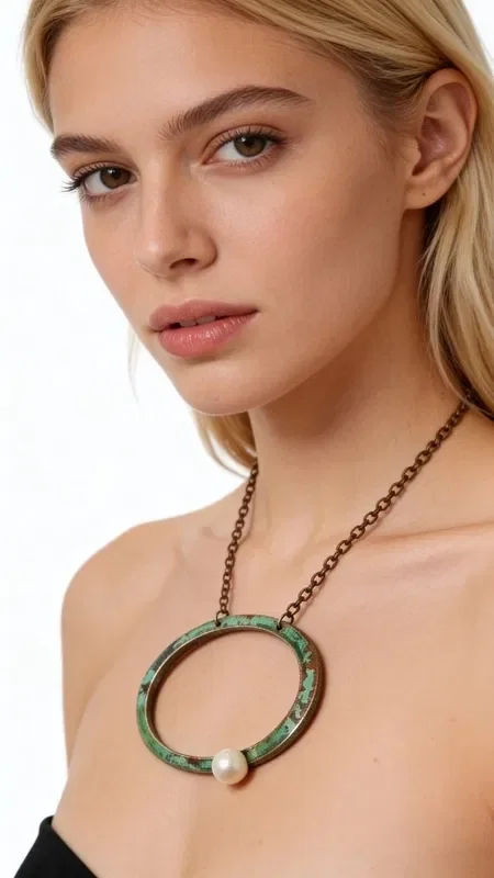 Discover the perfect balance between modern design and classic elegance with this large women's necklace featuring a pearl. Designed by Greek Jewelry Designer Aikaterini Chalkiadaki, this handmade piece combines the beauty of oxidized copper with the elegance of a fresh pearl.

The geometric circle shape creates a statement look that draws attention, while the shades of green copper give it a unique vintage character. The white pearl at the base of the necklace offers the perfect contrast, creating a striking result that pairs easily with any outfit.

Ideal for women who love large, eye-catching necklaces and are looking for jewelry with personality. It looks equally beautiful with casual or more formal looks, offering endless styling possibilities. Store in a dry place and clean gently with a soft cloth to preserve the natural oxidation of the copper.