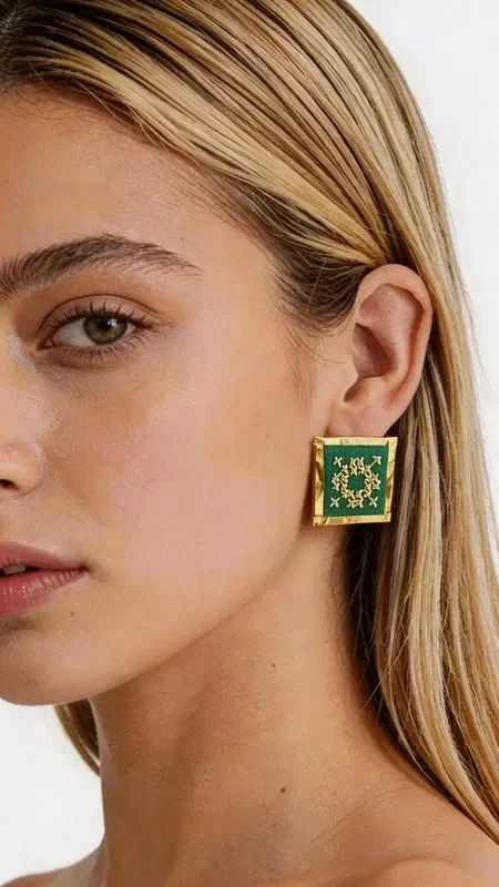 Stand out with these striking statement earrings, embroidered with gold thread in a vibrant green color that combines the traditional art of embroidery with a modern aesthetic. Designed by Greek Jewelry Designer Aikaterini Chalkiadaki, these handmade earrings feature geometric patterns inspired by Greek folklore. Each earring is a unique work of art, embroidered with detail and care.

The rich green color combined with gold accents creates a striking combination that suits both everyday and formal looks. Their square shape gives them a modern aesthetic, while the handmade construction guarantees high quality.

Ideal for every occasion, from casual outings to weddings and formal evening events. Pair them with monochrome outfits to highlight their beauty, or create bohemian looks that express your personality.

Material: Brass, Fabric
Care: Store in a dry place away from moisture and direct sunlight.