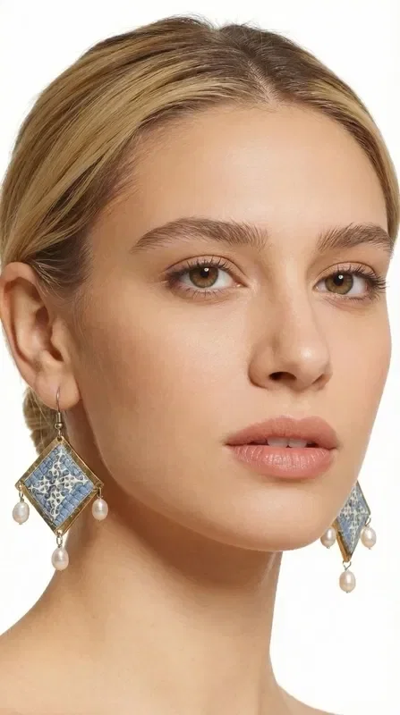 , These statement embroidered earrings in light blue with geometric patterns made of gold thread are the ideal handmade jewelry piece to highlight your uniqueness. These impressive dangle earrings, designed by Greek Jewelry Designer Aikaterini Chalkiadaki, combine the traditional art of embroidery with a modern aesthetic.

The light blue hue combined with the gold thread creates a refined contrast that catches the eye. The geometric patterns add a contemporary touch, while the delicate pearls hanging from the base of the earrings add movement and femininity. Their folklore design makes them ideal for special occasions, from bridal looks to cocktail parties. Perfect earrings for weddings, christenings, and special events. Care for them with attention, avoiding contact with water and perfumes for a longer lifespan.