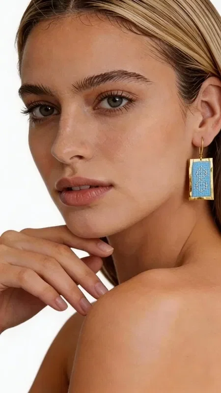 These statement embroidered earrings in light blue are the perfect choice for women who want to stand out with style and elegance. Designed by Greek Jewelry Designer Aikaterini Chalkiadaki, these striking handmade jewelry pieces combine a modern aesthetic with the traditional technique of embroidery.

The gold thread creates geometric patterns that beautifully frame the light blue color, giving them a unique shine and movement. The rectangular shape of the earrings offers a contemporary look, while the embroidered texture adds depth and character. They are ideal for special occasions and weddings, as well as for adding a sophisticated touch to everyday outfits.

Material: Brass, Fabric

Be sure to store them in a dry place and avoid contact with moisture to preserve their shine. Pair them with simple outfits to highlight their beauty.