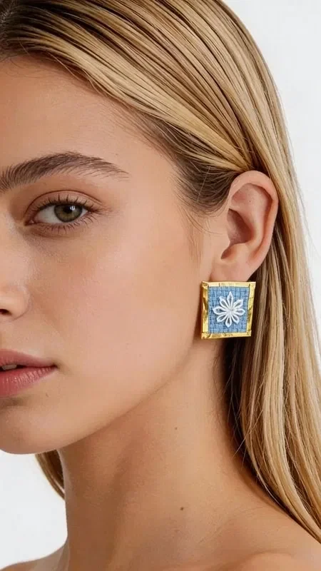 Discover the magic of embroidered statement earrings with geometric designs in gold thread on a striking light blue background. These exceptional handmade earrings, designed by Greek Jewelry Designer Aikaterini Chalkiadaki, combine the traditional art of embroidery with a contemporary aesthetic.

Each earring is adorned with intricate geometric motifs embroidered in gold thread on a vivid light blue background, creating a unique embroidery reminiscent of traditional Greek craftsmanship. The square shape and gold outline add an elegant touch that makes these striking earrings ideal for any occasion.

These statement earrings are perfect for completing a bridal look, an elegant festive appearance, or even a casual outfit you want to stand out. The high-quality craftsmanship and original design make them a unique piece that will elevate your style.

Material: Brass, Fabric

Handle with care, avoiding contact with water and perfumes to preserve the colors.