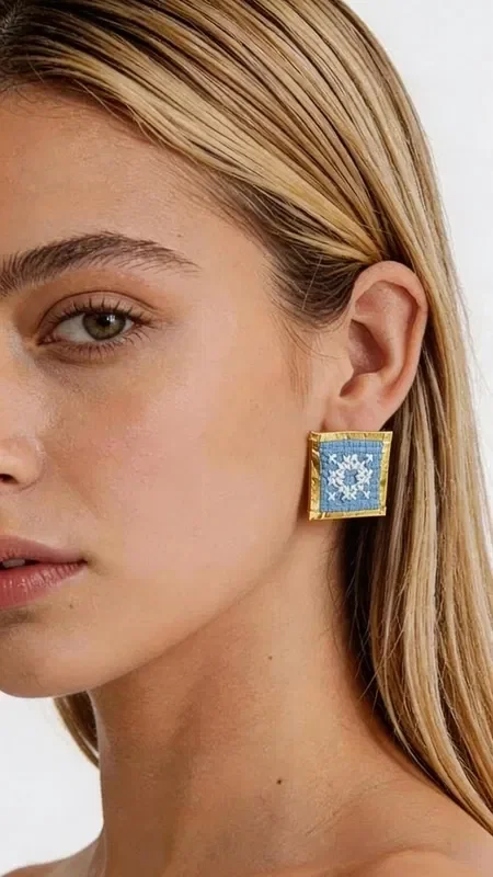 These statement embroidered earrings with geometric patterns in light blue will add a unique character to every look. These striking handmade earrings, designed by Greek Jewelry Designer Aikaterini Chalkiadaki, combine the traditional art of embroidery with contemporary geometric design.

The gold thread framing the embroidered light blue fabric creates a refined contrast that catches the eye. The square shape with folklore embroidery highlights Greek tradition through a modern aesthetic.

Each earring is handmade with special attention to detail, guaranteeing the high quality and uniqueness of the piece. Ideal for striking appearances, wedding events, or everyday styling that wants to stand out. They pair perfectly with boho outfits, classic dresses, and modern casual looks.

Material: Brass, Fabric

Take care of them with gentle cleaning and store them in a dry place to preserve their shine.