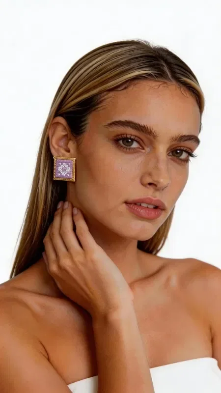 , Embroidered statement earrings with geometric patterns in lilac color are the perfect choice for women who want to stand out with style and elegance. Designed by Greek Jewelry Designer Aikaterini Chalkiadaki, these striking handmade earrings combine the traditional art of embroidery with contemporary design. The square shape with intricate geometric motifs creates a unique visual effect that complements any look. The gold thread used in the embroidery adds shine and luxury, while the lilac color adds a touch of femininity and elegance.

These statement earrings are ideal for special events, evening outings, or even for a bridal look. They pair perfectly with monochrome outfits and add a bold splash of color to any ensemble.

Material: Brass, Fabric

To preserve their beauty, store the earrings in a dry place and avoid contact with moisture and perfumes.