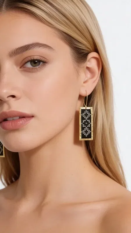The embroidered statement earrings with geometric designs, featuring gold thread on a black background, are a stunning piece of jewelry that combines traditional embroidery art with a modern aesthetic. Designed by Greek Jewelry Designer Aikaterini Chalkiadaki, these handmade earrings carry a strong personality and a distinct Greek character.

The rectangular shape with intricate geometric motifs creates a striking visual contrast between the deep black background and the gold thread. Each earring is hand-embroidered with special attention to detail, resulting in a unique piece of jewelry that stands out from the ordinary.

These statement earrings are ideal for special occasions and looks that call for elegance and style. They pair perfectly with black or gold outfits, adding a touch of Greek tradition to any look. Handle them gently and store them in a dry place to preserve their shine.