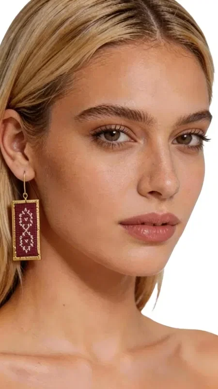 The statement embroidered earrings with geometric patterns in burgundy color are the perfect combination of traditional craftsmanship and contemporary aesthetics. Made from high-quality gold thread, these striking earrings were designed by Greek Jewelry Designer Aikaterini Chalkiadaki, capturing authentic Greek jewelry artistry.

The rectangular embroidered earrings feature intricate geometric motifs that create a refined vintage aesthetic. The deep burgundy color blends harmoniously with the gold details, creating a luxurious result that suits every occasion perfectly.

The handmade construction guarantees the uniqueness of each piece, while their light weight makes them ideal for all-day wear. These boho earrings are the perfect choice for weddings, special events, or to add a touch of elegance to your everyday look.

Material: Brass, Fabric

Take care of your earrings by avoiding contact with water and perfumes. Store them in a dry place to preserve their shine.