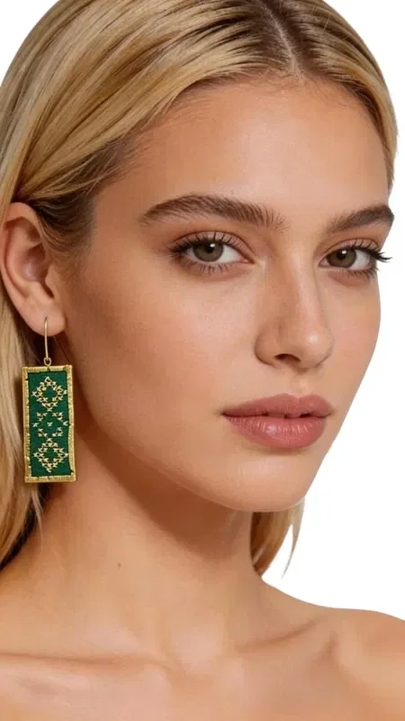 Stand out with these striking statement earrings that combine the traditional art of embroidery with modern design. Designed by Greek Jewelry Designer Aikaterini Chalkiadaki, these unique embroidered earrings in a vivid green color are the perfect choice for any distinctive look. The rectangular earrings are adorned with geometric motifs embroidered with gold thread, creating a refined color combination that suits both casual and formal looks. The handmade construction ensures the uniqueness of each piece, while their light weight makes them particularly comfortable to wear. Material: Brass, Fabric. To preserve the colors and quality, store the earrings in a dry place and avoid contact with moisture and chemicals.