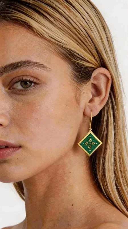 These striking embroidered statement earrings with a geometric design will become the ultimate accessory for every look. Their square shape in a green shade with golden details creates a unique aesthetic that combines modern style with the traditional art of embroidery.

Designed by Greek Jewelry Designer Aikaterini Chalkiadaki, these handmade earrings stand out for the exceptional quality of the gold thread and the contemporary interpretation of geometric motifs. The green color adds freshness and vibrancy, while the golden details highlight the elegance of the design.

These dangle earrings are ideal for evening outings, special occasions, or whenever you want to add a touch of style to your everyday look. Their unique shape and color scheme make them completely versatile, pairing perfectly with monochrome outfits and adding an impressive character.

Material: Brass, Fabric

Care for your earrings by storing them in a dry place and gently cleaning them with a soft cloth.