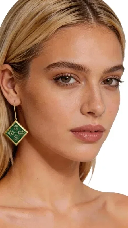 Striking embroidered statement earrings that combine the traditional art of embroidery with contemporary geometric design. Designed by Greek Jewelry Designer Aikaterini Chalkiadaki, these unique handmade earrings in green will become the focal point of any outfit. The refined diamond shape with its detailed gold-thread embroidered motifs creates an elegant contrast with the vivid green color. Each earring is handmade with special attention to detail, combining folklore design elements with a modern aesthetic. Ideal for weddings, special occasions, or whenever you want to add a touch of color and elegance to your everyday look. Their lightweight design makes them comfortable for all-day wear. Store the earrings in a dry place, avoiding contact with water and chemical products to preserve their shine and beauty.