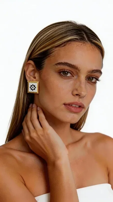 The embroidered statement earrings with geometric patterns in gold thread on white fabric are the perfect choice for the woman who seeks striking and modern jewelry. Designed by Greek Jewelry Designer Aikaterini Chalkiadaki, they combine the traditional art of embroidery with contemporary aesthetics.

Each earring features a square shape with a refined geometric motif embroidered in gold thread on a white base. The folklore design creates a unique contrast that adds elegance and character to every look.

These handmade earrings are ideal for weddings, special occasions, or as an everyday statement piece. The high quality of craftsmanship and carefully selected materials guarantee durability and comfortable wear. Their lightweight design makes them suitable for all-day wear, while their size adds just the right amount of glamour without being overdone.

Material: Brass, Fabric

Take care of your earrings by avoiding contact with water and perfumes. Store them in a dry place to preserve their shine.