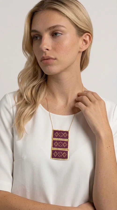 The embroidered necklace in deep burgundy is a statement piece that instantly draws attention and transforms any outfit into something special. Designed by Greek Jewelry Designer Aikaterini Chalkiadaki, this handmade necklace combines the tradition of Greek embroidery art with a contemporary aesthetic, creating a result that is both timeless and unique.

The necklace features three rectangular fabric sections in rich burgundy, each adorned with delicate geometric patterns in gold thread — inspired by the folk tradition of Greek embroidery. The gold-toned brass frame enhances its striking presence, while the slender gold chain lends an elegant balance between bold and feminine.

Ideal for both casual and formal occasions alike, it pairs perfectly with a white t-shirt, a black dress, or even an office outfit. A perfect gift for women who love large, striking jewelry with soul and story.