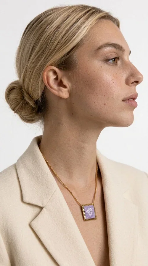 The embroidered lilac necklace with geometric patterns is a statement piece that combines the traditional art of embroidery with a modern aesthetic, creating a result that instantly stands out. Designed by Greek Jewelry Designer Aikaterini Chalkiadaki, this handmade necklace is the perfect blend of folklore inspiration and contemporary style.

The rectangular pendant in lilac shades features detailed geometric motifs embroidered on fabric, framed by gold-tone brass that adds elegance and structure. The gold box chain harmoniously completes the look, while the larger size of the pendant makes it ideal for those who want to make a statement with their style.

Wear it with casual or formal outfits — it pairs equally well with a linen dress for a summer stroll and a blazer for a professional look. An ideal gift for every woman who loves unique, handmade jewelry with a Greek soul.