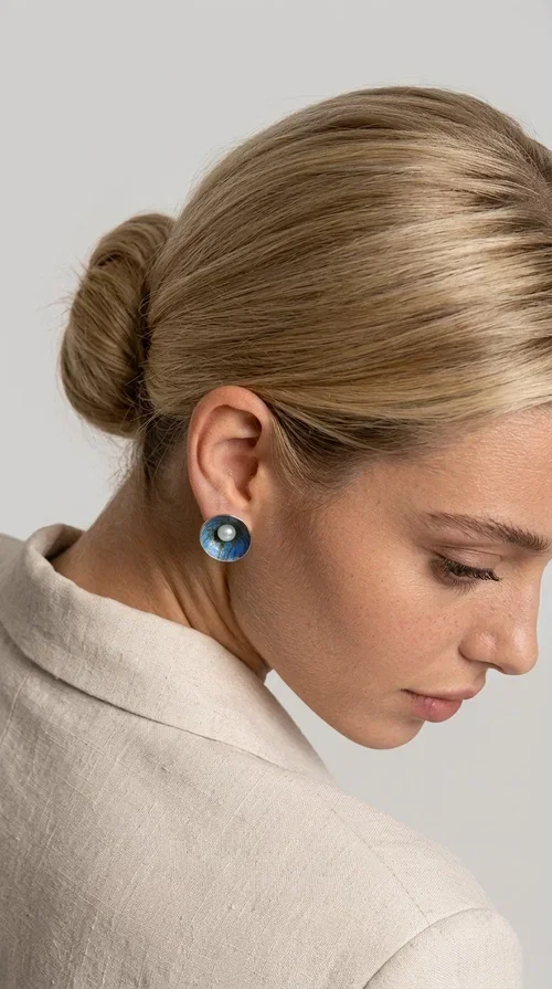 The handmade stud earrings with a pearl in deep blue enamel are an ideal choice for every woman seeking elegance with character. Designed by Greek Jewelry Designer Aikaterini Chalkiadaki, these unique earrings combine the traditional technique of enamel with the timeless grace of the pearl, creating a result that impresses without being overwhelming.

The circular brass body is covered with handmade enamel in rich shades of blue — from deep navy to cobalt — with subtle color variations reminiscent of the ocean depths. At the center, a white pearl adds finesse and contrast, elevating the whole piece to another level. The result is a statement piece of jewelry that suits an everyday look just as well as a wedding or formal outfit.