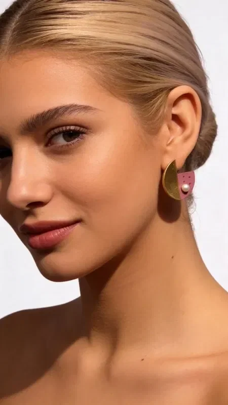 Discover the unique beauty of these stud earrings with pearls and pink color, a striking piece of jewelry that combines modern aesthetics with classic elegance. These handmade earrings by Greek Jewelry Designer Aikaterini Chalkiadaki stand out for their geometric shape and impressive color combination.

Made from premium brass and adorned with natural pearls, these women's earrings showcase a distinctive aesthetic that sets them apart. The pink hue blends harmoniously with the golden details, creating a boho chic look that enhances any outfit. Perfect for everyday wear as well as special occasions.