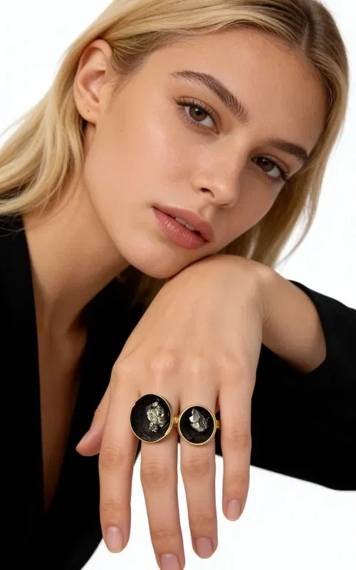 Discover the magic of the handmade women's ring with pyrite, a unique piece of jewelry that combines the power of natural stones with modern aesthetics. Designed by Greek Jewelry Designer Aikaterini Chalkiadaki, this striking ring is the perfect choice for women seeking statement jewelry with character.

The oval silhouette of the ring is surrounded by golden brass, while the center is dominated by a black patina that holds a natural iron pyrite stone. The pyrite offers metallic reflections that create a mesmerizing visual dialogue with the black background.

The large size of the ring makes it ideal for those who prefer striking jewelry that stands out. The handmade construction guarantees the uniqueness of each piece, making it a true work of art.